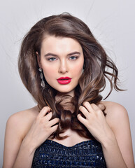 Beautiful girl with long wavy hair. Brunette with curly hairstyle. Professional Makeup. Fashion Earrings. - 541460885