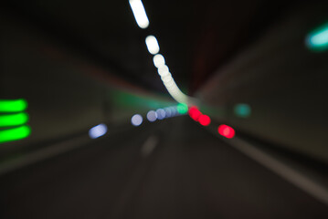 Colorful defocused bokeh lights in blur at night in tunnel, driving in austria