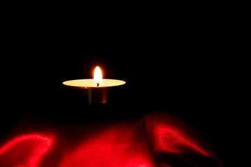 Candle light and red fabric background in the darkness with space for text or image. valentine love concept