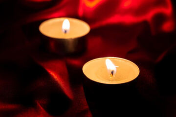 Candle light and red fabric background in the darkness with space for text or image. valentine love concept