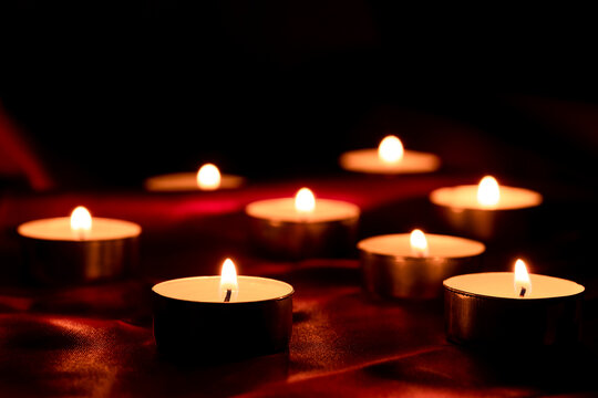 Candle light and red fabric background in the darkness with space for text or image. valentine love concept