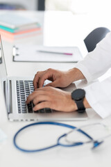 close up of a doctor typing on a laptop computer