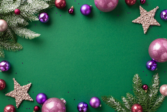 New Year concept. Top view photo of violet and pink baubles sparkle star ornaments spruce branches in hoarfrost and purple sequins on isolated green background with copyspace in the middle