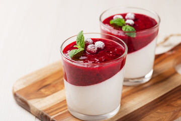 Vegan dairy free coconut Panna cotta with cranberry sauce in glasses on white wooden table. Healthy...
