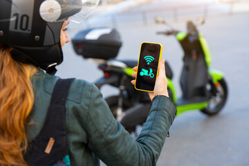 Woman connecting an electric motorcycle with the smartphone