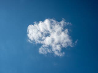 A simple little white cloud under a beautiful blue sky. The cloud occupies the center of the photograph