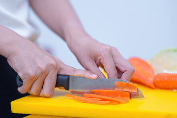 Young woman cooking romantic dinner at home cutting vegetables close-up ,Closeup of human hands cooking vegetables salad in kitchen on the glass table with reflection
