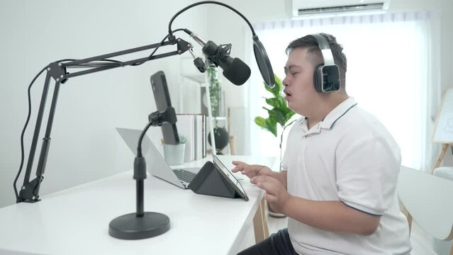 Down syndrome DJ puts on headphones and speaks in a microphone in his home studio.