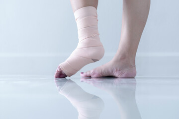 Woman holding her leg with sprained ankle and elastic bandage isolated on white background. ankle bandage - obrazy, fototapety, plakaty