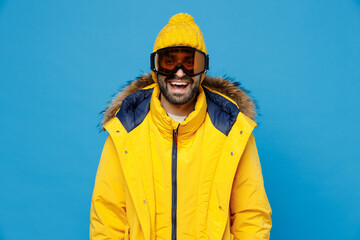 Young skier man 20s wearing yellow puffer down jacket with fur hood googles mask look camera...