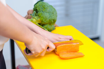 Young woman cooking romantic dinner at home cutting vegetables close-up ,Closeup of human hands cooking vegetables salad in kitchen on the glass table with reflection
