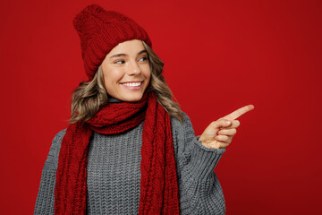 Young woman wear warm grey sweater scarf hat point index finger aside on workspace area mockup...