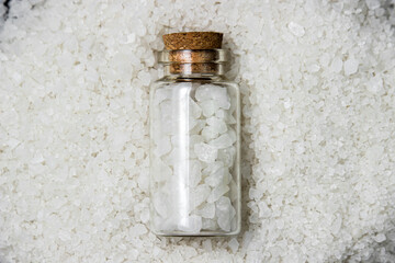 Coarse rock salt on a black background. Rock salt in a glass flask