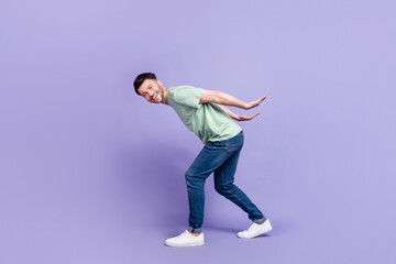Fototapeta na wymiar Full length photo of nice young man carry empty space back toothy smile dressed stylish gray garment isolated on purple color background