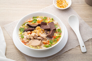 Chicken Porridge,rice soup with sliced chicken breast,blood curd and dried shiitake mushrooms in white bowl.Asian breakfast style