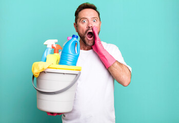 middle age man feeling shocked and scared. housekeeper with clean products