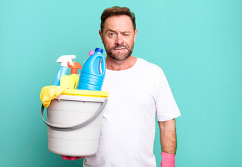 middle age man looking puzzled and confused. housekeeper with clean products