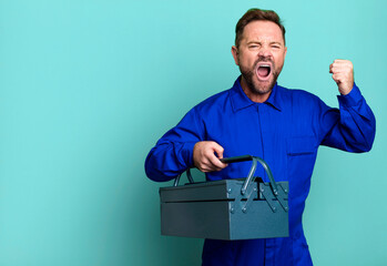 middle age man shouting aggressively with an angry expression. plumber with a toolbox concept