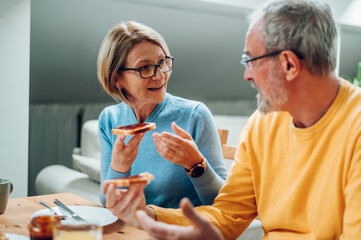 Senior couple eating breakfast at home and spending morning together