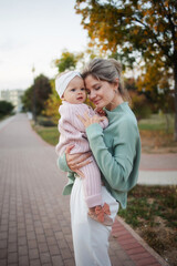 Young mother of mixed race American hugs her daughter. A stylish mother walks in an autumn park. Concept: Mother's Day, Young Mother, Motherhood. 10 month old baby girl