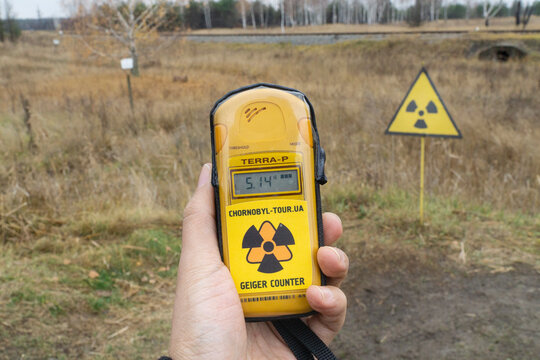 Close up to a geiger counter with radiation levels and a radioactive logo sign at background at chernobyl disaster exclusion zone