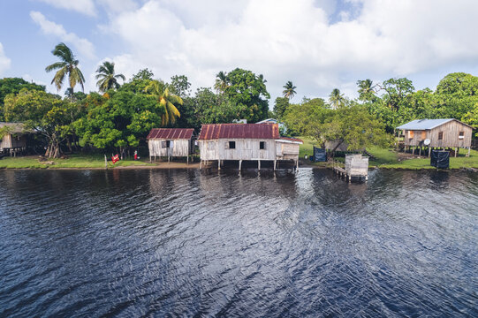 Arial Shot Of Cute Small Village On The Shores Of A Clear Sea Surrounded By Forests And Palm Trees