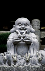 Buddhist monk rock statue standing and holding rabbits also surrounded by other rabbits as a representation of Rabbit Shio(Year of Rabbit)