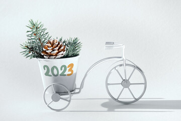 2023 caption, greeting on white decorative bike. Bicycle with pine cone and fir twigs in decorative...