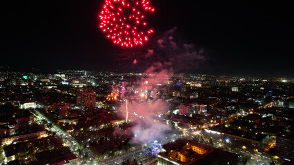 Huge bright flashes from fireworks in the city center. Aerial view from a drone on the night city...
