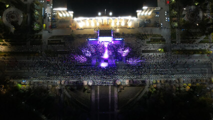 Top view from a drone of a big concert in the night city. Lots of people, rays of light. A large...