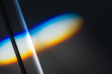 Sunbeam with spectrum colors lays over white wall,