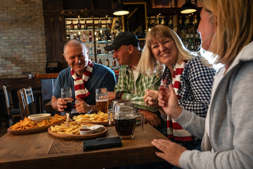 Senior football and soccer fans drinking beer at the pub, cheering and celebrating scores.	
