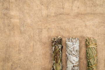 white sage, mugwort and siskiyou cedar incense bundles on a textured bark paper with a copy space, aromatherapy concept