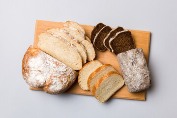 Freshly baked bread slices on cutting board against white wooden background. top view Sliced bread
