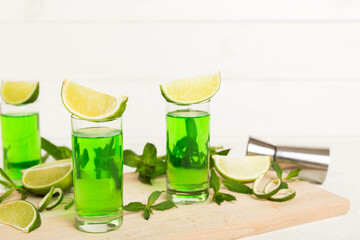 Sweet refreshing mint liqueur, with ice and mint leaves on table background, Shots with lime slice and mint flat lay