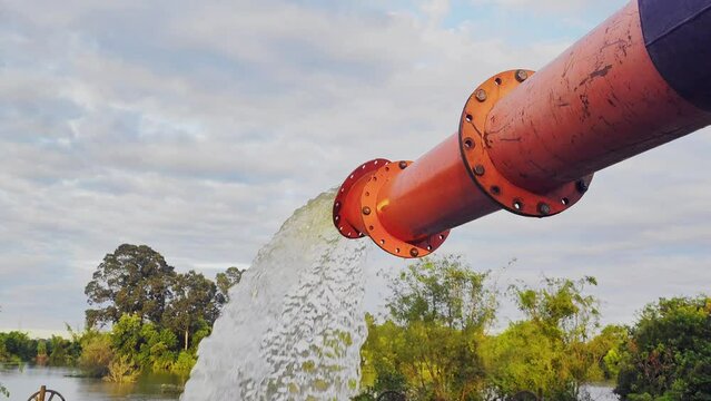 A large orange drain is pumping water. Selective focus and close up objects