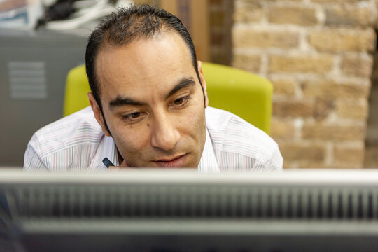 The Media Agency: Office Worker. A mature male business professional concentrating on his computer monitor screen. From a series of related images.