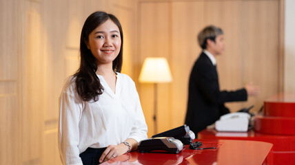 Friendly receptionist woman working at desk in hotel lobby. Leisure and travel at holidays....