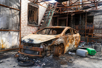 Fototapeta premium War in Ukraine. 2022 Russian invasion of Ukraine. Countryside. A destroyed burnt-out civilian car stands near a destroyed house. No people. War crimes