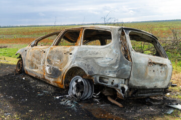 War in Ukraine. 2022 Russian invasion of Ukraine. Countryside. A destroyed burnt-out civilian car stands on the side of the road. No people. War crimes