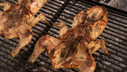 Barbecue outdoor. Roasting a whole chicken in the metal grill with charcoal fire. Delicious crispy meat.