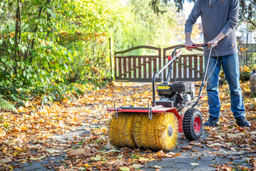 Kehrmaschine mit Bürstenaufsatz im Herbst bedienen