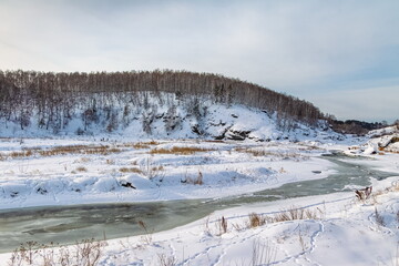 Winter landscape with trees and sky from the high rocky river bank