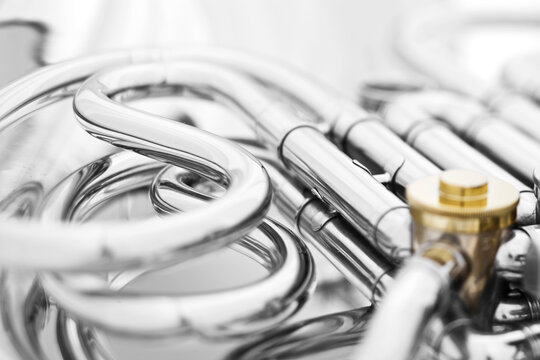 Detail of the curved complex pipes of a French Horn with a white background.