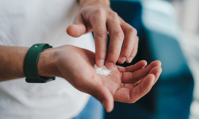 Close-up view of a man's hands holding the cream he applies to his face before going to bed. Skin...