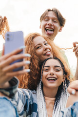 Portrait of active young people taking a selfie together standing in a funny position making different facial expressions having fun together. Summer vacation