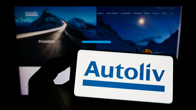 Stuttgart, Germany - 10-23-2022: Person holding mobile phone with logo of automotive supply company Autoliv Inc. on screen in front of business web page. Focus on phone display.