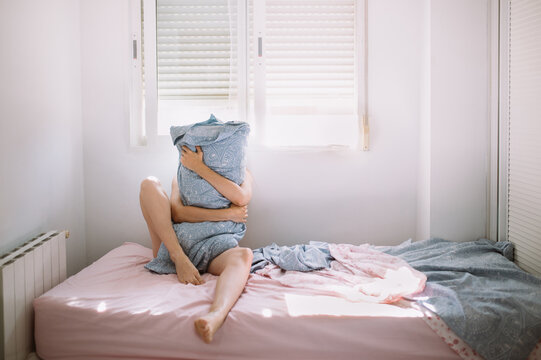Anonymous woman hugging pillow on bed