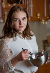 A girl prepares a cream for a festive Christmas cake in a kitchen decorated for Christmas
