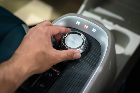 Hand of the driver is controlling on a button to change gearing of the modern luxury car. Transportation action and equipment object photo, selective focus.